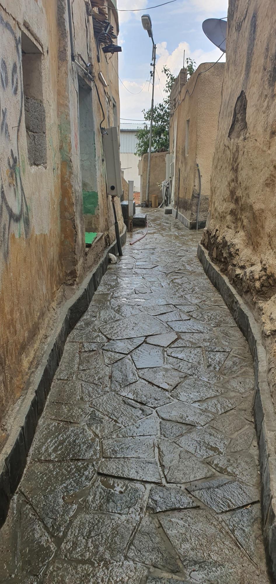 ممر ضيق بأرضيات حجرية بعد التطوير في البسطة